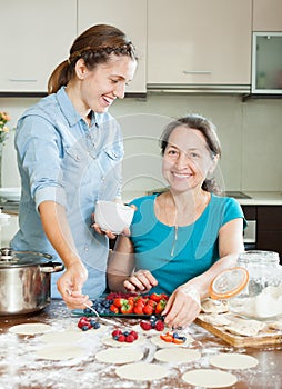 Two women making sweet vareniki with berries