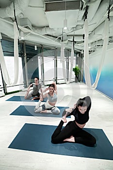 Two women and man doing yoga on sport mats together