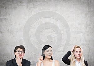 Two women and a man near a concrete wall