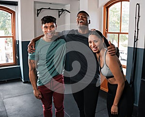 Two women and a man smiling in gym, showing shoulders and muscle in leisure wear
