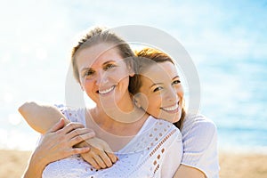 Two women mother and adult daughter enjoying vacation on the beach