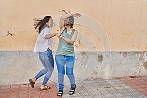 Two women mother and daughter smiling confident dancing at street