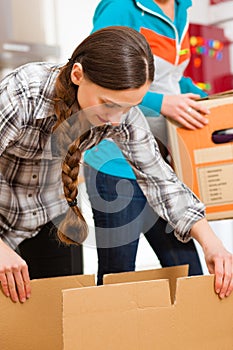 Two women with moving box in her house