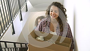 Two Women Moving Into New Home Carrying Box Upstairs