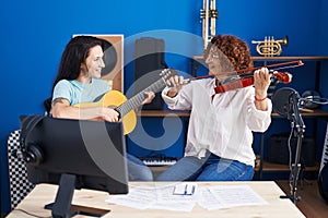 Two women musicians playing classical guitar and violin at music studio