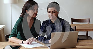 Two women, office employees using laptop, prepare on-line presentation