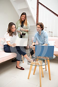 Two women and one man businessmen working informally on their computers in their office chairs