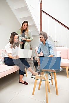 Two women and one man businessmen working informally on their computers in their office chairs