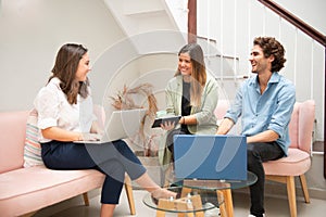 Two women and one man businessmen working informally on their computers in their office chairs photo