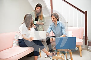 Two women and one man businessmen working informally on their computers in their office chairs photo