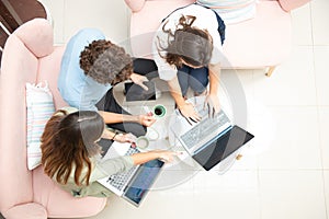 Two women and one man businessmen working informally on their computers in their office chairs