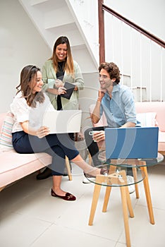 Two women and one man businessmen working informally on their computers in their office chairs photo