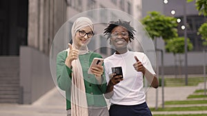 Two women, one in muslim clothes and african american, friends smiling while looking at camera