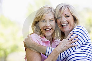 Two women outdoors hugging and smiling