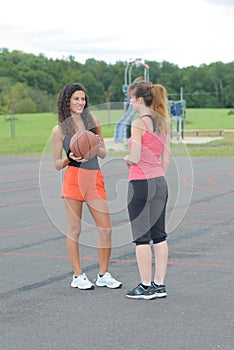 Two women in park holding basketball