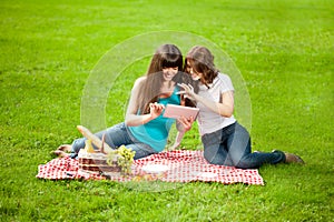 Two women in the park on a picnic with a Tablet PC