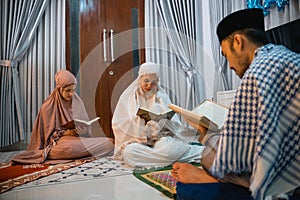 two women participants read the Quran following male recitation leader