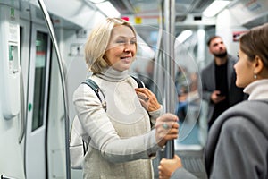 Two women passengers talking in subway car on way to work