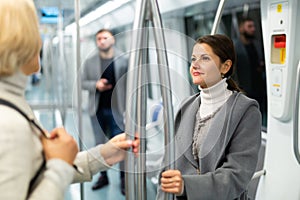 Two women passengers talking in subway car on way to work