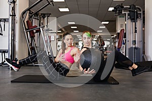 Two women passing weighted medicine ball, abs crunch and core exercise