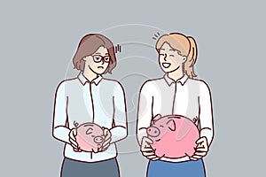 Two women with piggy banks for money of various sizes for concept of income inequality
