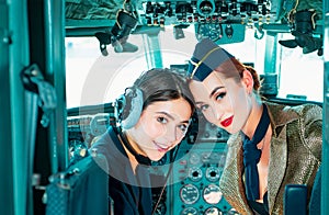 Two women Pilots Sitting in Cabin of Modern Aircraft. Smiling stewardess in the aircraft. Portrait of attractive woman