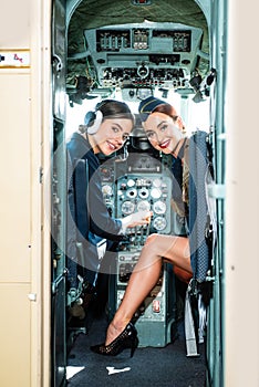 Two women pilots smiles and wishes a successful flight. Trainee Pilot and Flight Instructor in an Aircraft Cockpit. she
