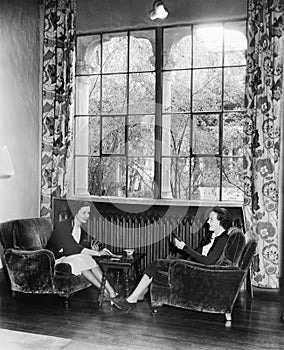 Two women playing cards and sitting together photo