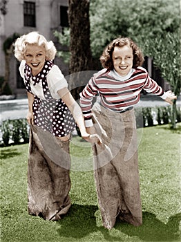 Two women playing a game of potato sack racing