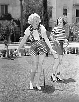 Two women playing horse shoes together