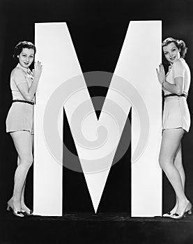 Two women posing with huge letter M photo