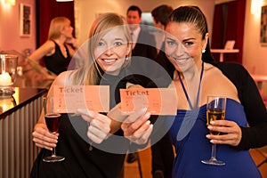 Two women presenting theatre or movie tickets