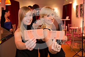 Two women presenting theatre or movie tickets