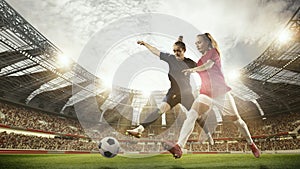 Two women, professional football, soccer players in motion during match, game at 3d open air stadium arena with blurred