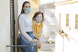 Two women with protective masks in balcony