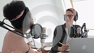 two women in a recording studio creating audio content, recording a podcast or radio show