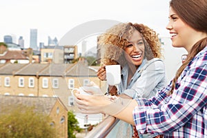 Two Women Relaxing On Rooftop Garden Drinking Coffee