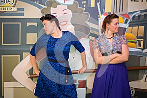 Two women in retro-style dresses looking in