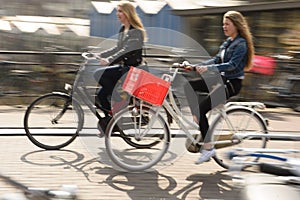Two Women Ride their bikes to work in Amsterdam, Netherlands