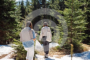 Two women in roe deer clothes walk on a snowy trail in the mountains, active recreation at a mountain resort in the spring