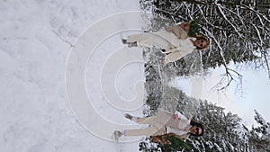 Two women are running along a snowy forest road with fir branches in their hands