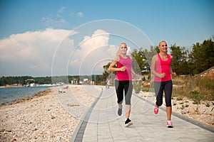 Two women athlets running on the beach - early morning summer w