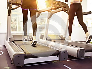 Two women running on treadmill in gym