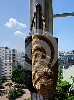 Two women\'s bags in black and beige raffia on the balcony