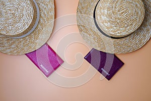 Two women`s beach straw boater hats, passports on a beige background. Trip, travel and tourism concept