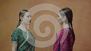 Two women in sari looking into each other`s eyes