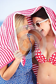 Two Women Sheltering From Sun On Beach Holiday