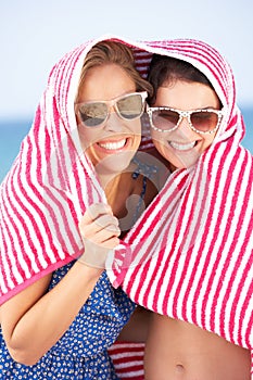 Two Women Sheltering From Sun On Beach Holiday