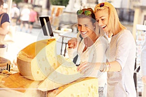 Two women shopping for cheese on food market