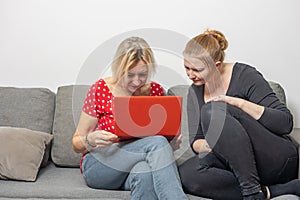 Two women shopping via laptop at home